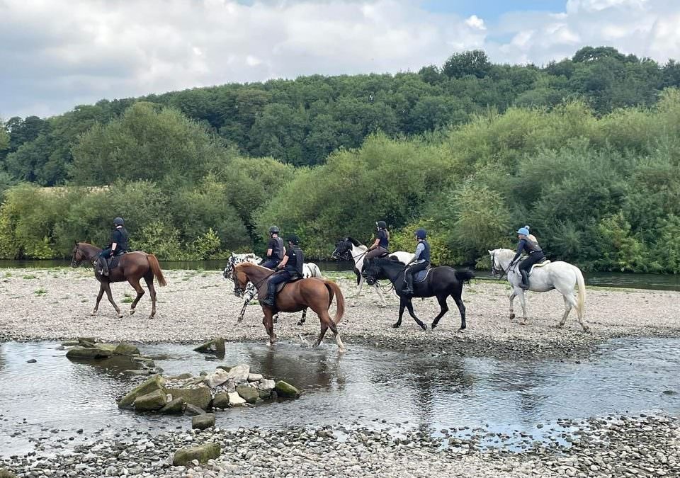 A group of horses and riders down by the river Severn